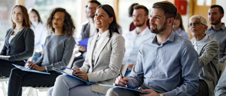 Group of people sitting at a presentation taking notes