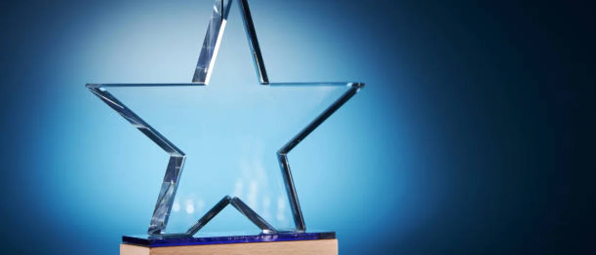Clear star shaped crystal on wooden base against blue background