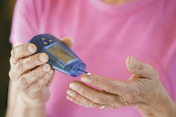 patient in pink shirt self-administering glucose metering test on finger