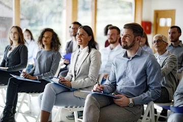Group of people sitting at a presentation taking notes 