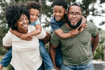 Parents carrying kids on their backs and smiling