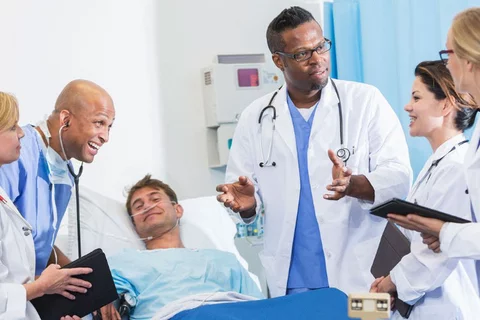 A team of doctors discussing something with a patient on the hospital bed