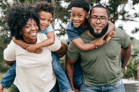 Parents carrying kids on their backs and smiling