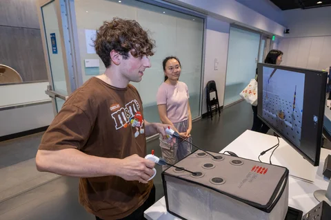 a student working with the invented device. he's using a monitor to see the location of the needles.