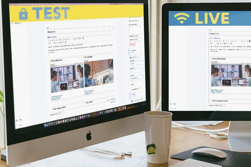 Two monitors on a desk: the left shows a site in edit mode with a 'live' banner, the right shows the same site with a 'test' banner.