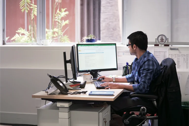 A person working at a desk with two computer monitors