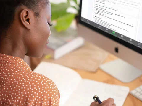 Woman writing notes at computer