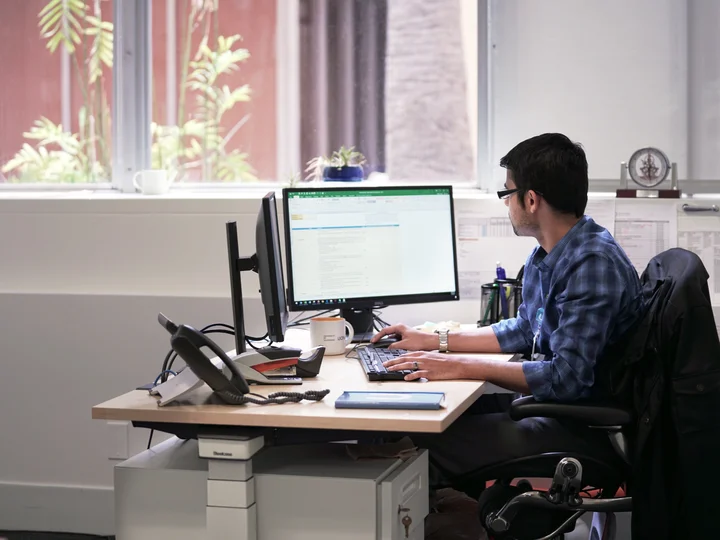 A person working at a desk with two computer monitors