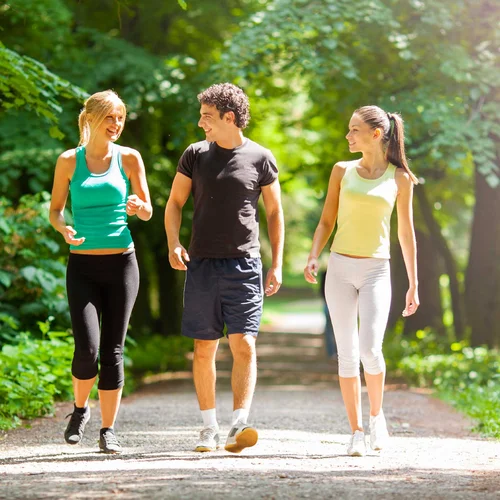 2 women and a man walking on a trail with trees in the background