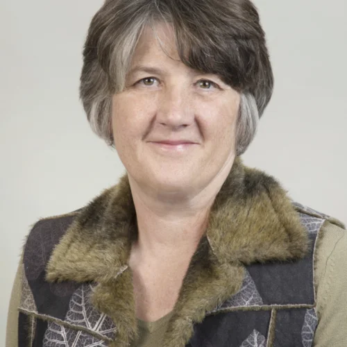 Portrait of a girl with short grey hair and a furry collar smiling 
