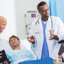 A team of doctors discussing something with a patient on the hospital bed