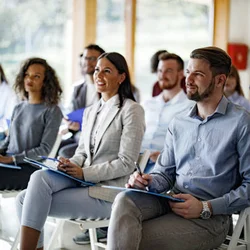 Group of people sitting at a presentation taking notes 