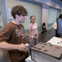 a student working with the invented device. he's using a monitor to see the location of the needles.