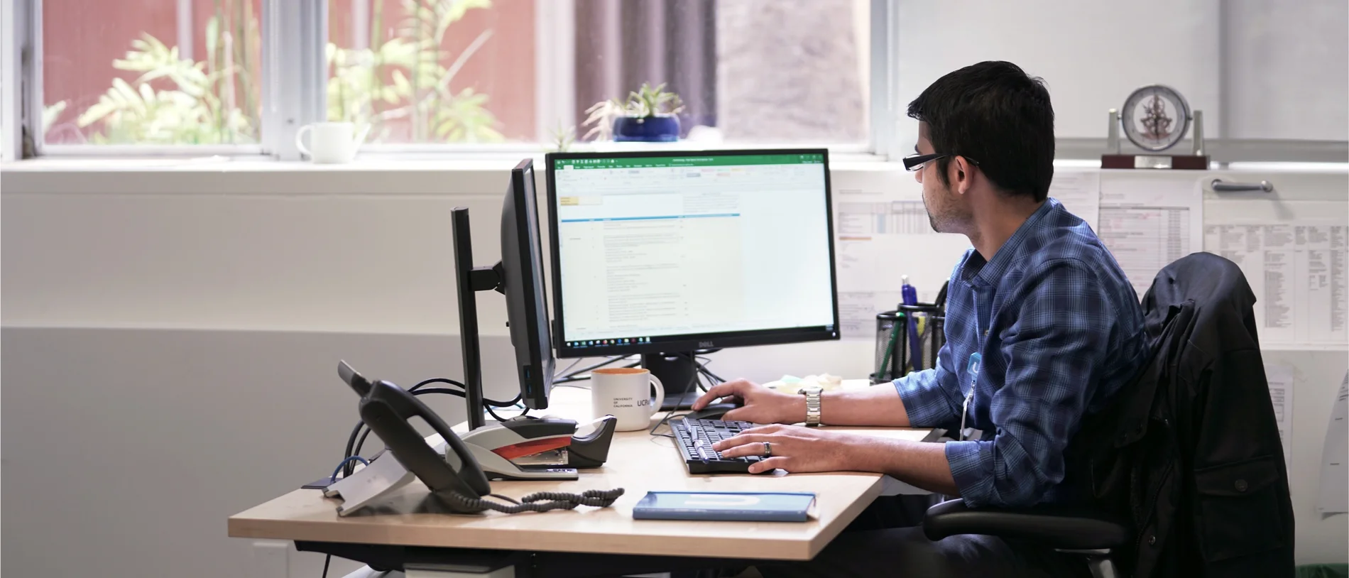 A person working at a desk with two computer monitors
