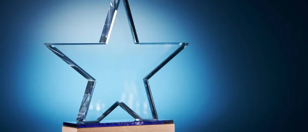 Clear star shaped crystal on wooden base against blue background