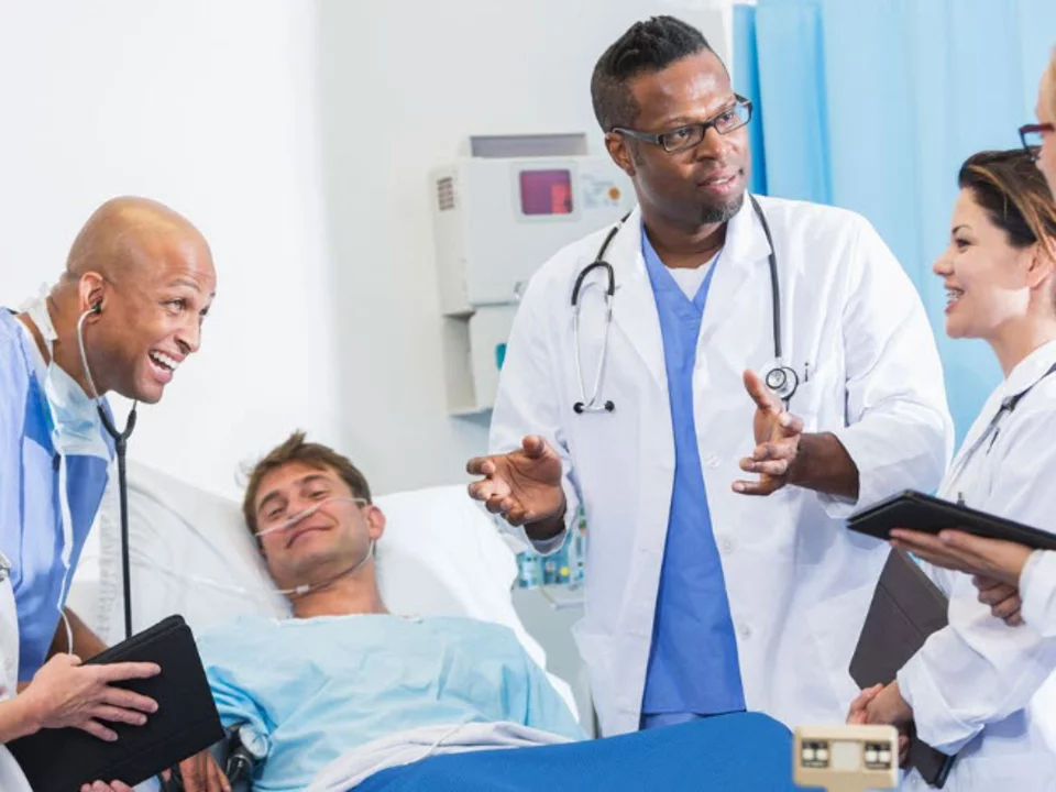 A team of doctors discussing something with a patient on the hospital bed