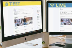 Two monitors on a desk: the left shows a site in edit mode with a 'live' banner, the right shows the same site with a 'test' banner.