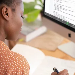 Woman writing notes at computer
